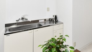 A kitchen with a double sink, a coffee maker, and a potted plant. - Suzumaru Hotel - Hostel (Wakayama)