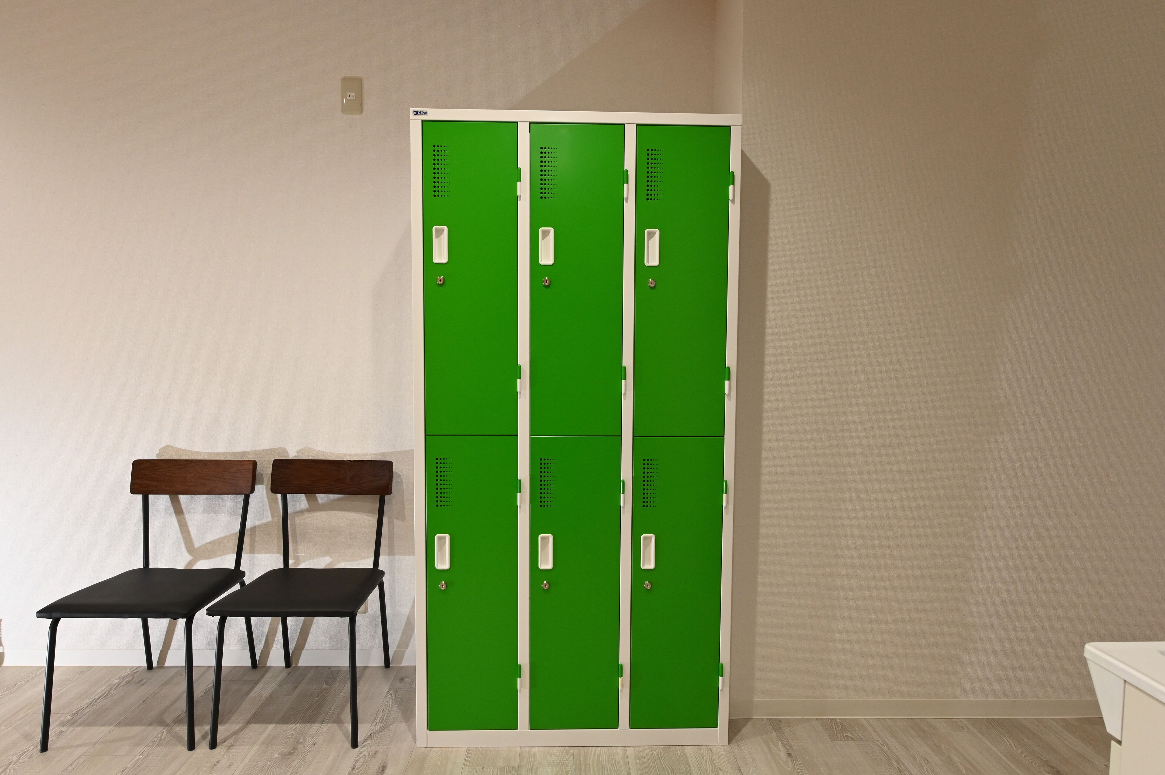 Een kamer met een groene kast en twee houten stoelen.