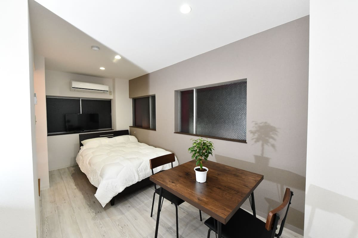A modern bedroom with a bed, bedside table, and a potted plant.