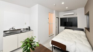 A compact bedroom with a bed, bedside table, and a window. - Suzumaru Hotel - Hostel (Wakayama)