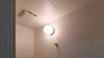 A small, dimly lit bathroom with a bathtub, a shower, and a toilet.
