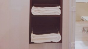 Une étagère verticale en bois sur laquelle sont empilées horizontalement cinq serviettes blanches.