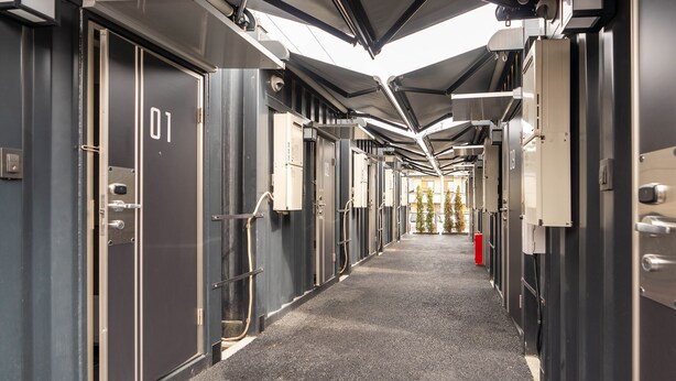 A corridor with doors labeled with numbers, a carpeted floor, and overhead lighting.