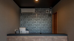 A reception area with a modern design, featuring a reception desk, an air conditioning unit, and a patterned wall.