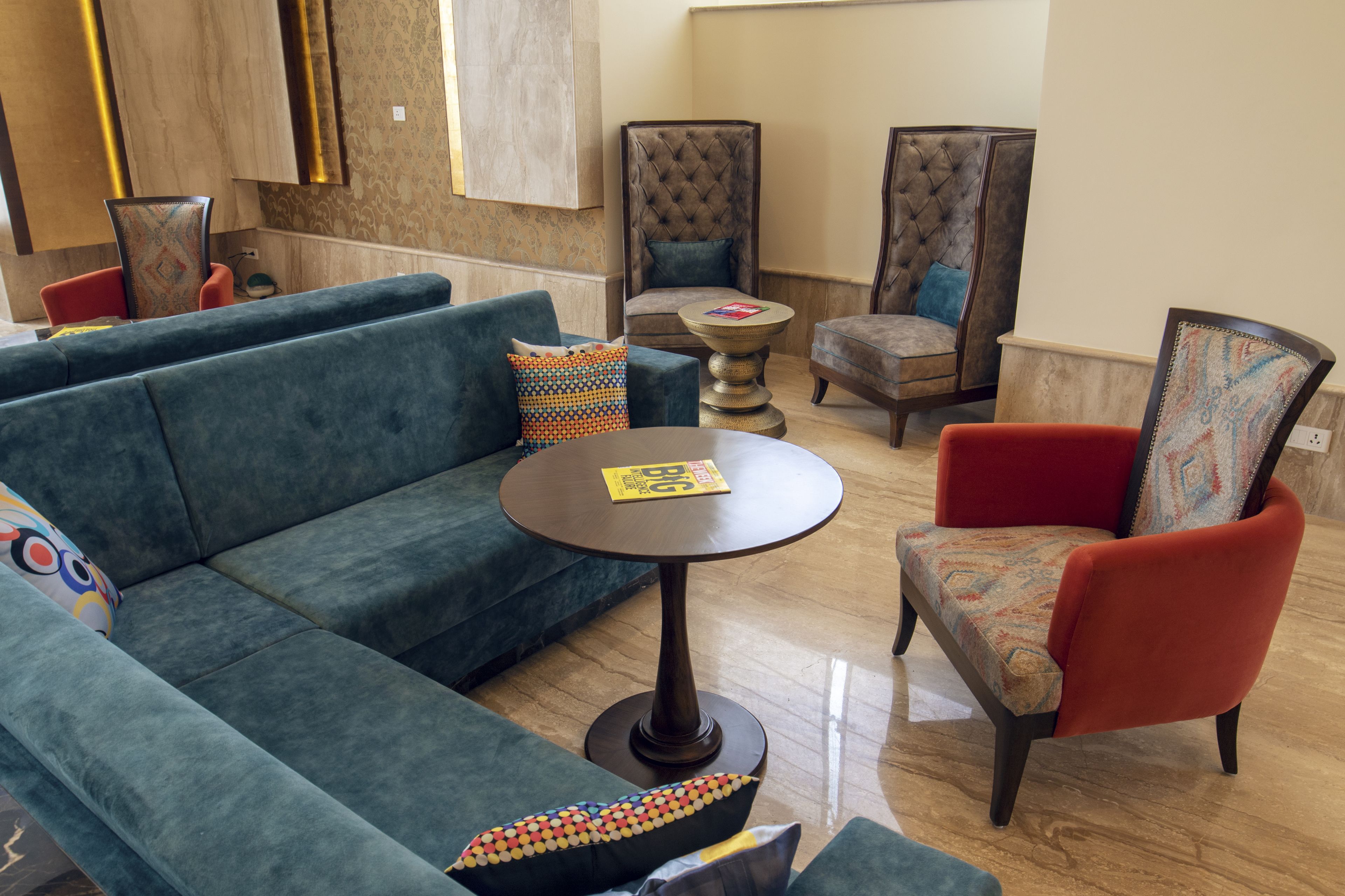 A lounge area with a blue sofa, red armchair, and a round table with a magazine.