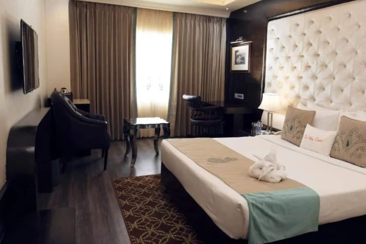 A hotel room with a large bed, a desk, a chair, and a television.