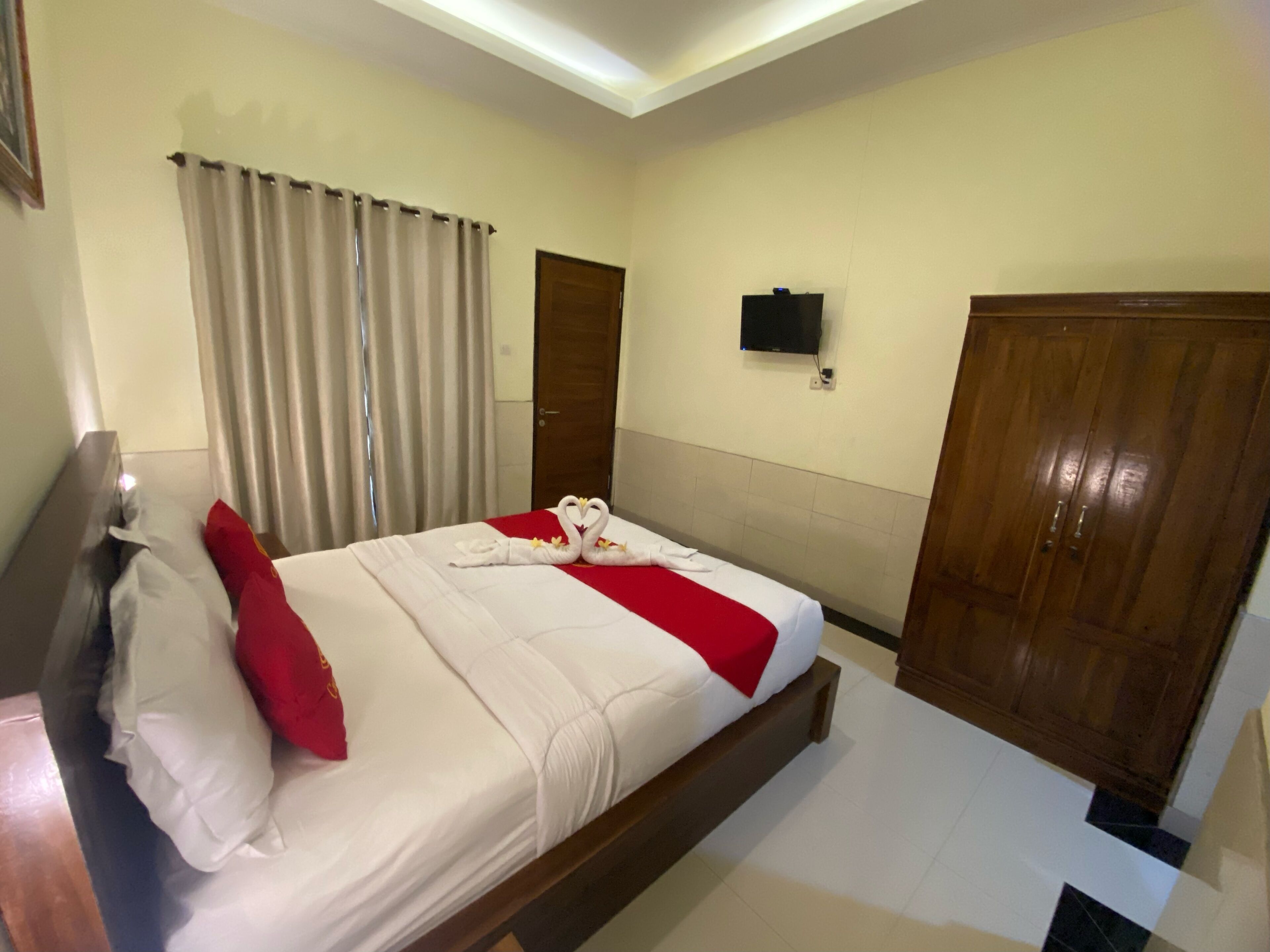 Habitación de hotel con cama, cortinas, televisor y armario.