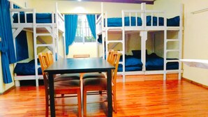 Una habitación con literas, una mesa y sillas.