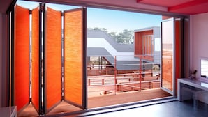 Un interior moderno con un amplio ventanal corredera que da a un espacio exterior con bancos de madera y una estructura metálica.