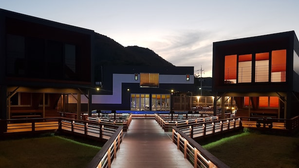 Un sendero de madera que conduce a un edificio con amplios ventanales y diseño moderno.