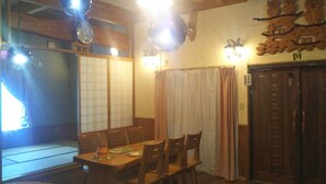 Perinteinen japanilainen huone, jossa on tatamimatto, matala pöytä tuoleineen ja liukuvat ovet.