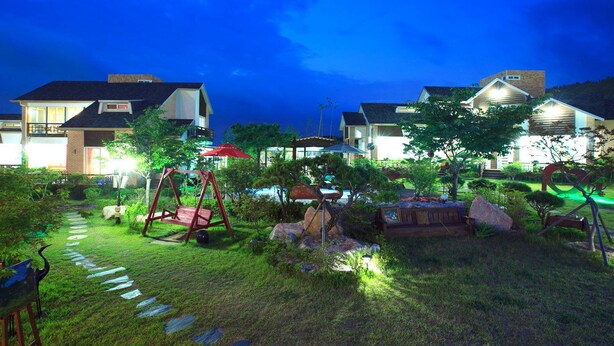 A residential area with houses, a swing set, and a garden path. - Gyeongju Orsay Pension (Gyeongju)