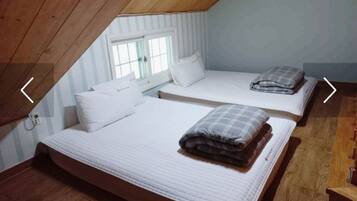 Een knus slaapkamer op zolder met twee bedden, houten balken en een raam.