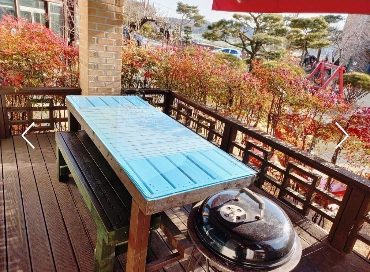 Um deck de madeira com uma mesa azul e um churrasqueira.