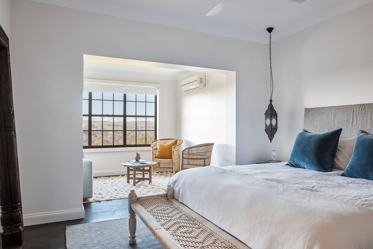 Ein Schlafzimmer mit einem großen Bett, einem Fenster mit Blick, einem Sessel und einem kleinen Tisch.