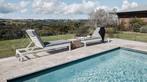 A swimming pool with lounge chairs and a view of the countryside. - 99 Acres Bangalow Retreat (Bangalow)