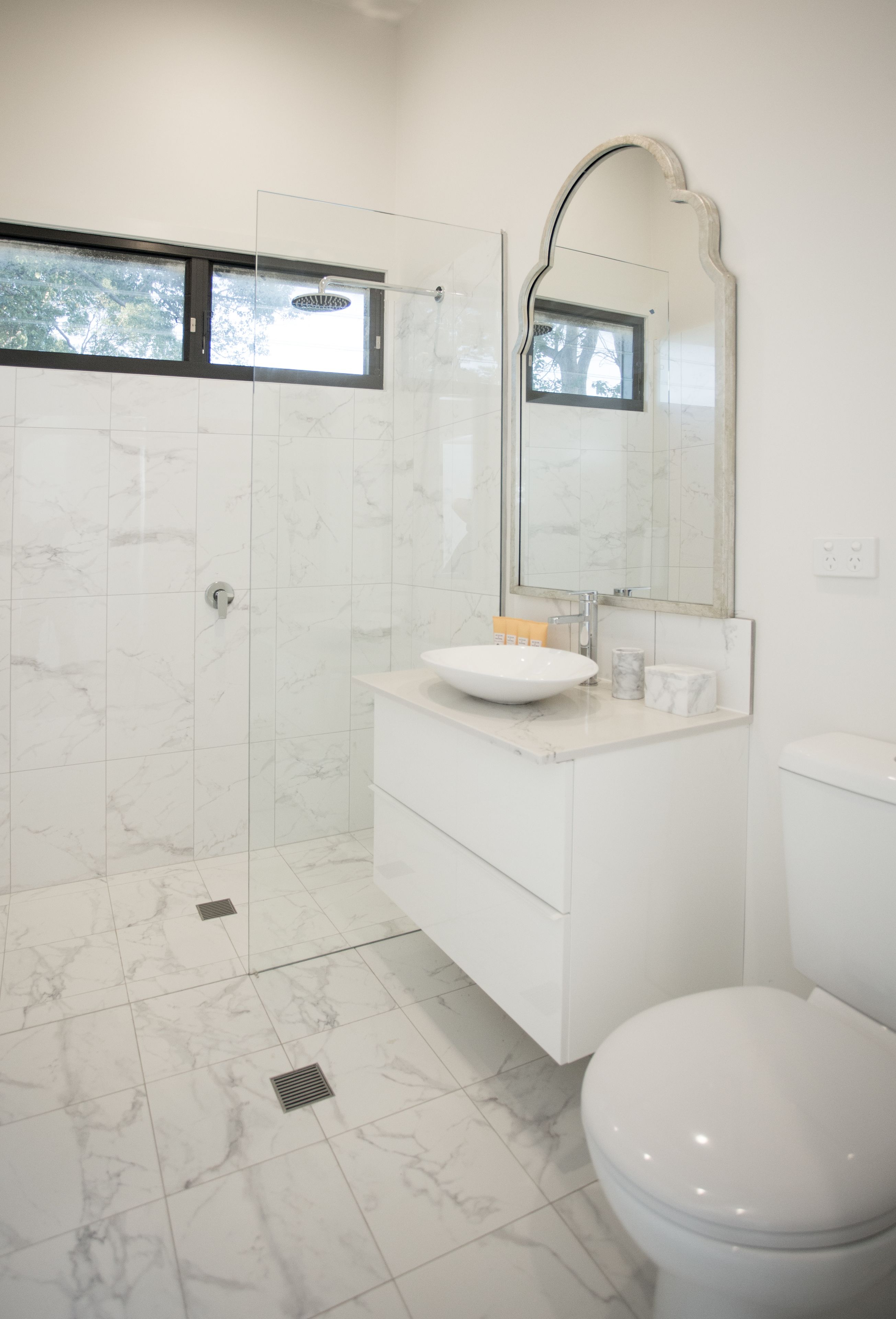 A modern bathroom with a glass-enclosed shower, a white sink, and a toilet.