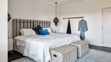 Une chambre à coucher bien rangée, avec un grand lit, une table de chevet, un luminaire suspendu et une armoire.