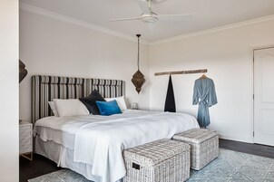 Un dormitorio ordenado con una cama grande, una mesita de noche, una lámpara colgante y un armario.