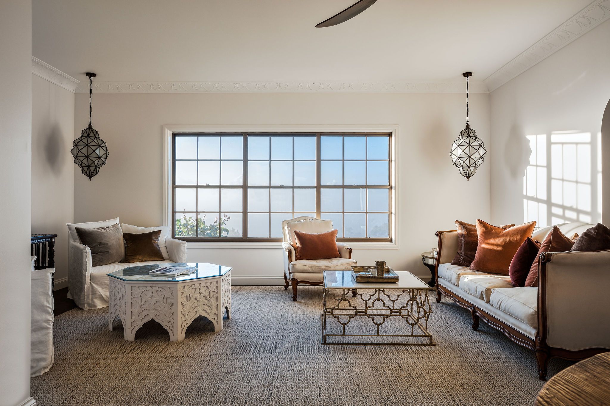 A spacious living room with a large window, a sofa, a chair, and a coffee table.