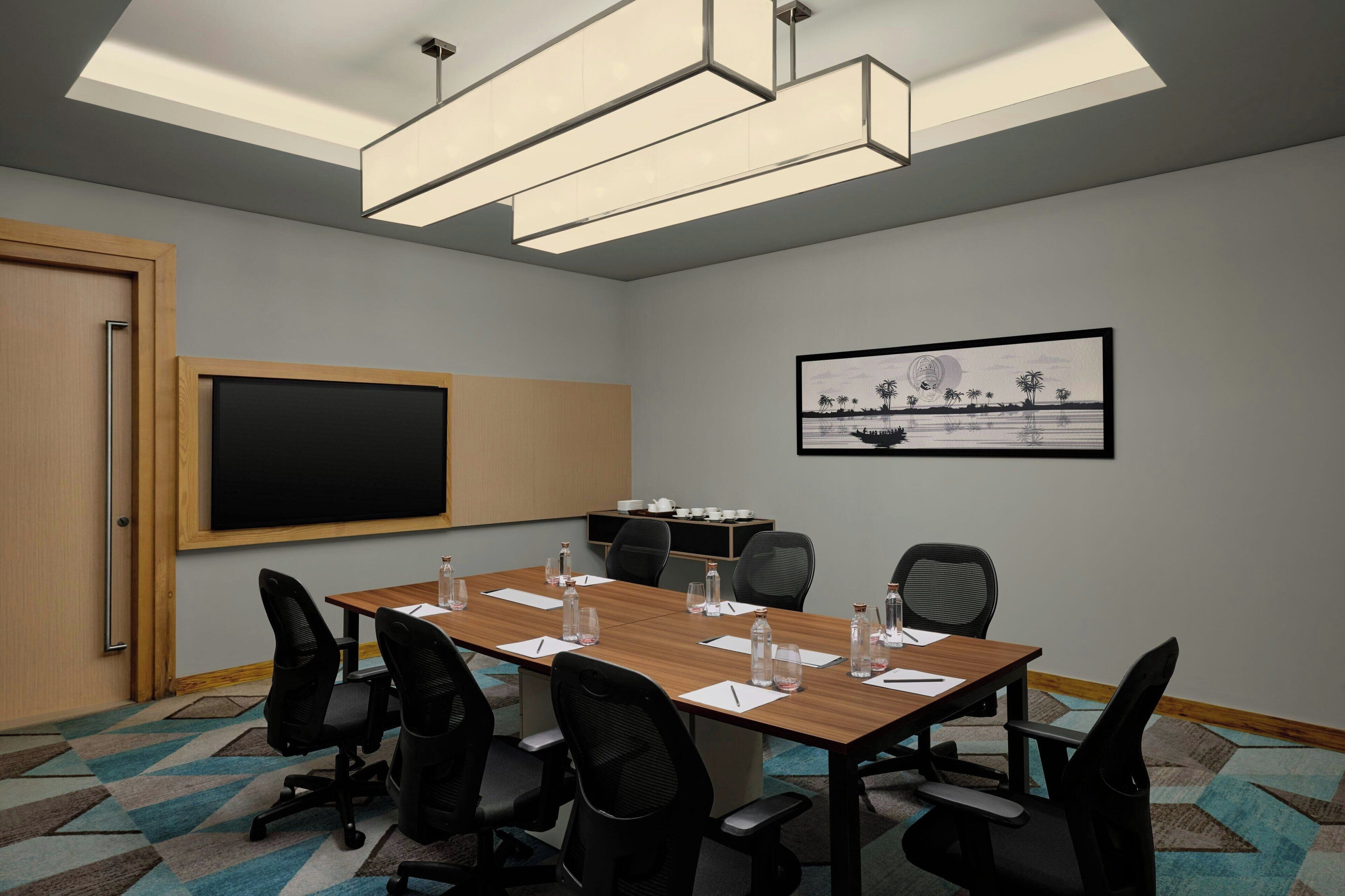 A conference room with a large table, chairs, a blackboard, and a framed picture on the wall.