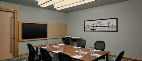 A conference room with a large table, chairs, a blackboard, and a framed picture on the wall.