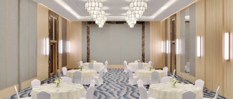 Un salón de conferencias con mesas redondas, sillas blancas y candelabros.