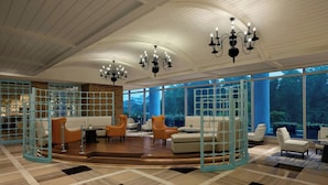 Un vestíbulo amplio con una zona de estar central, ventanas grandes y un techo alto con candelabros.