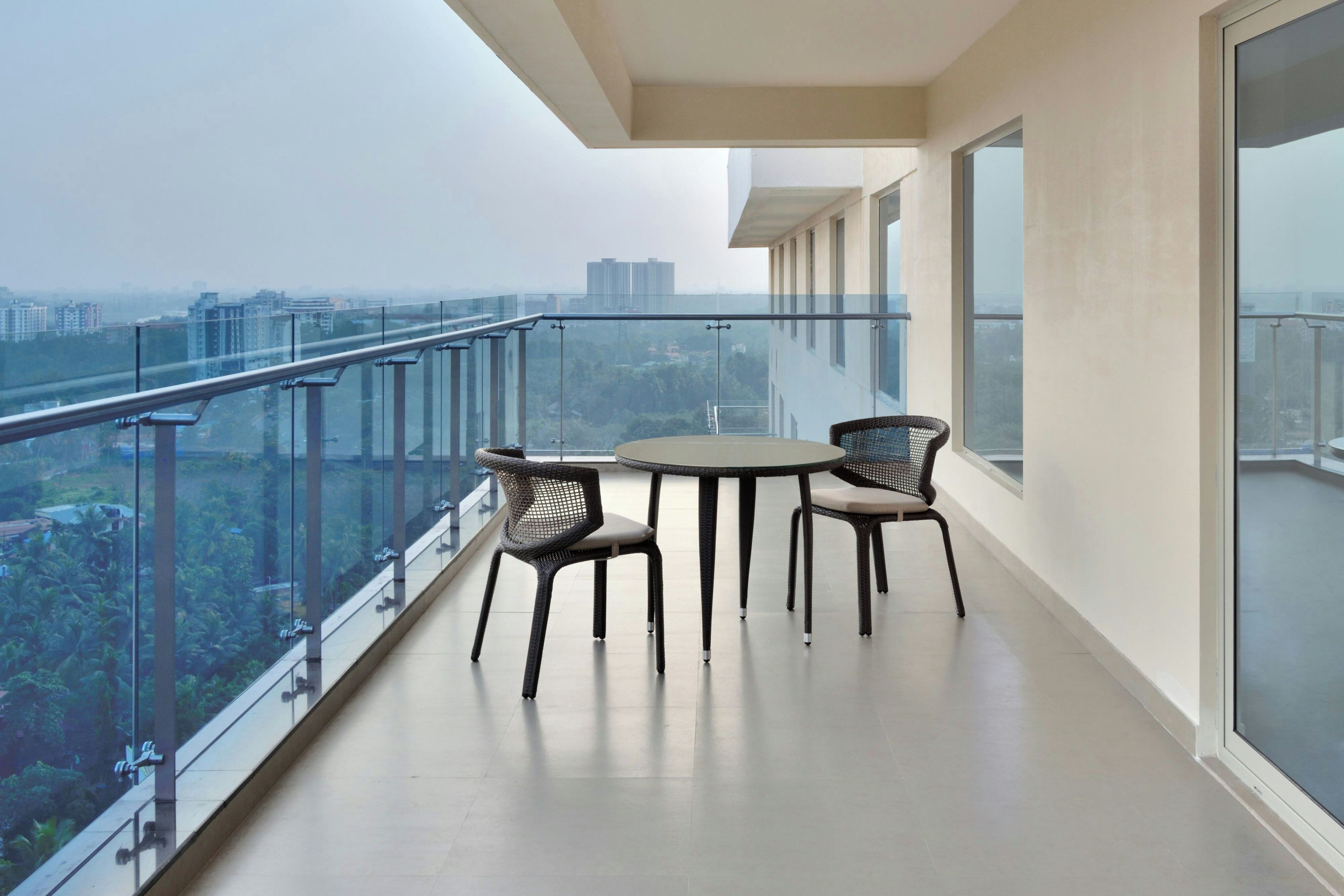 A balcony with a glass railing, a round table, and four chairs.