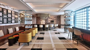 Un bar moderno con suelo a cuadros, taburetes de bar, un sofá y una pared decorada con elementos enmarcados.