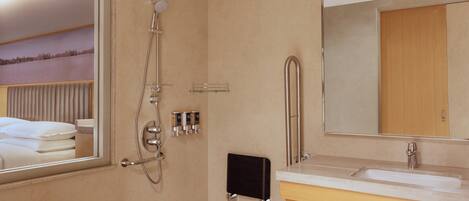 A modern bathroom with a large mirror, a shower, a sink, and a towel rack.