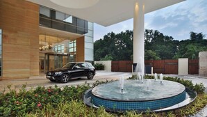 Un edificio moderno con una fuente, un coche y un jardín.