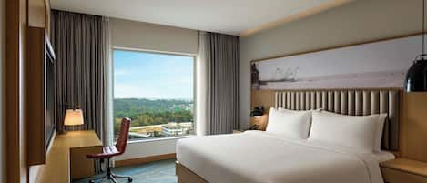 A hotel room with a large bed, a desk with a chair, a nightstand, and a view of the outdoors.