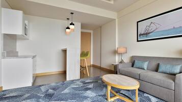 A modern living room with a grey sofa, a round wooden coffee table, and a blue patterned rug.
