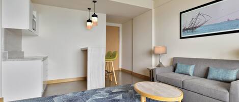 A modern living room with a grey sofa, a round wooden coffee table, and a blue patterned rug.