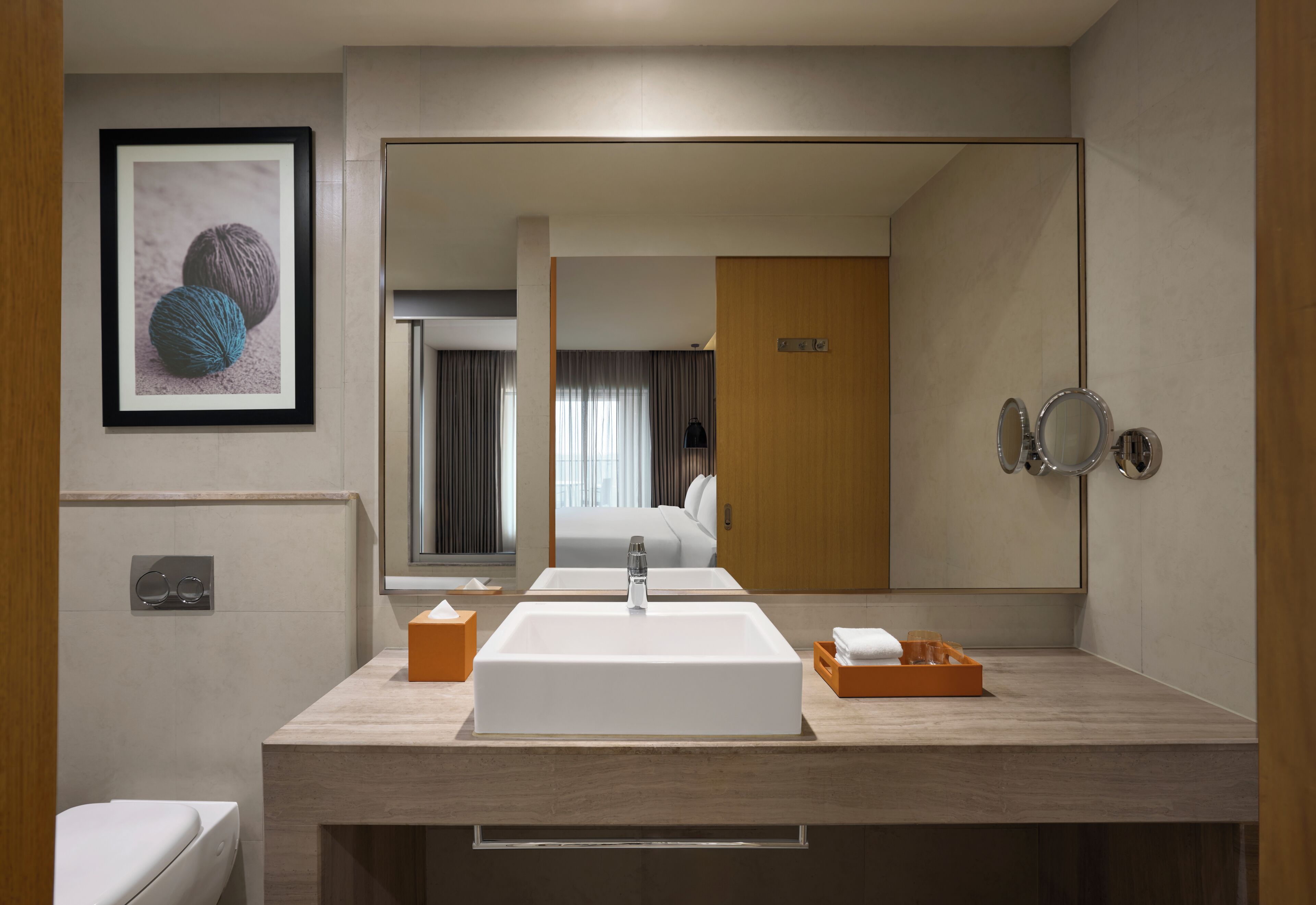 A modern bathroom with a large mirror, a sink, and a framed picture on the wall.
