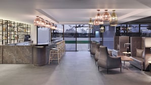 Un área de bar moderna con mostrador de mármol, taburetes de madera y luminarias contemporáneas.