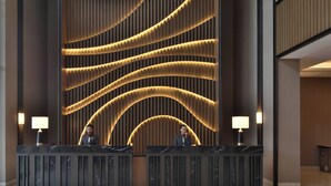 Un mostrador de recepción con dos empleados, un diseño de pared moderno y una encimera de mármol.