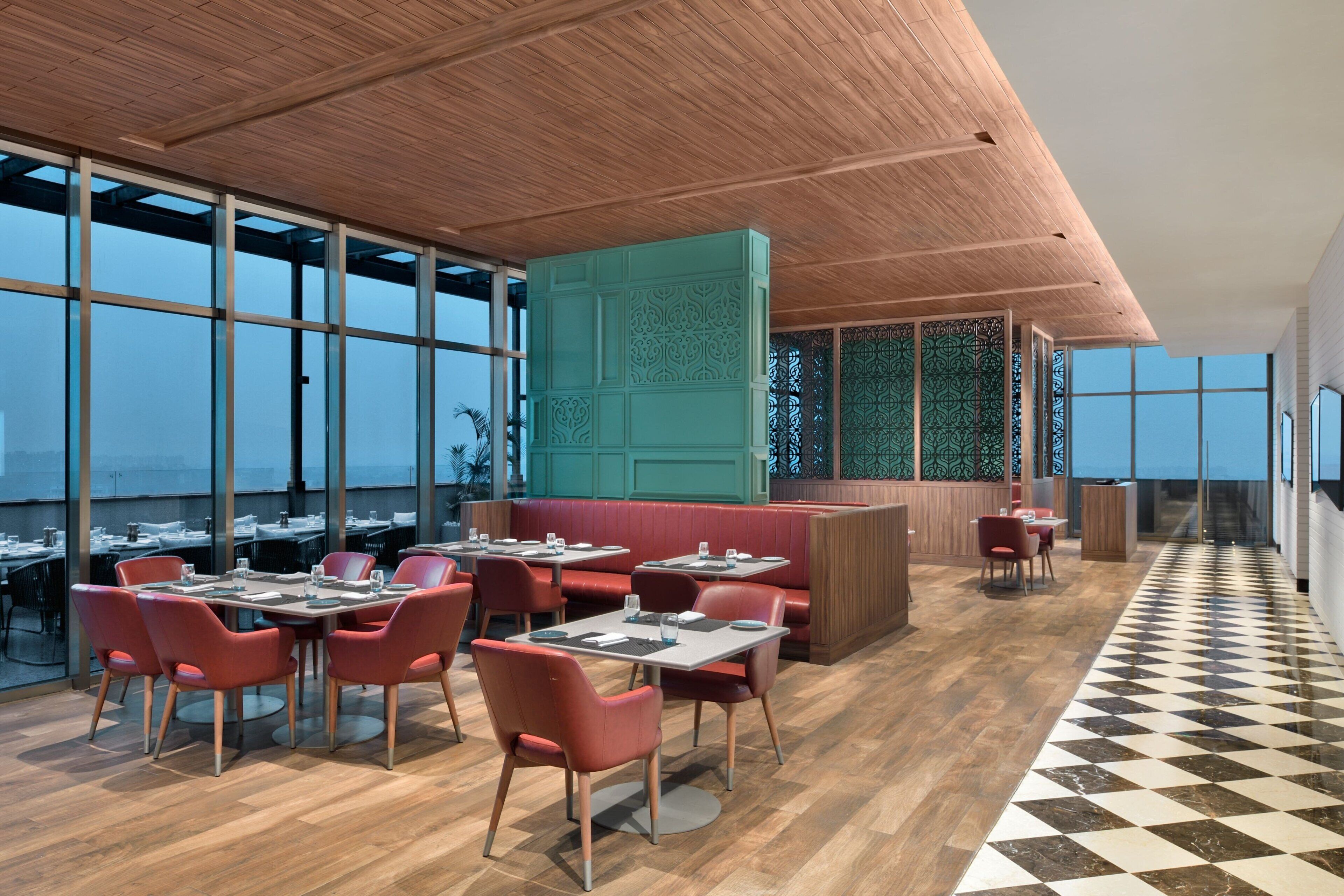 A modern restaurant with high ceilings, large windows, and a checkered floor.