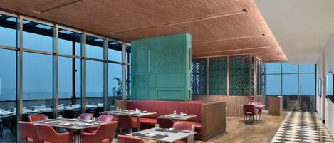 A modern restaurant with high ceilings, large windows, and a checkered floor.