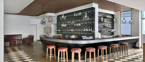 Un área de bar moderna con suelo a cuadros, techo de madera y taburetes.