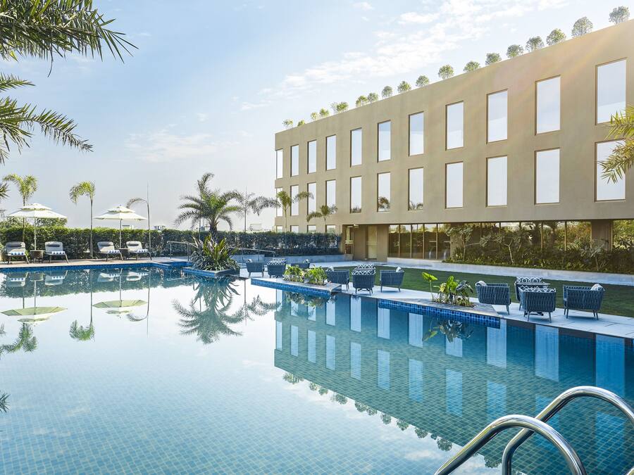 Ein modernes Hotel mit Schwimmbad, Liegestühlen und einem Gebäude mit großen Fenstern.