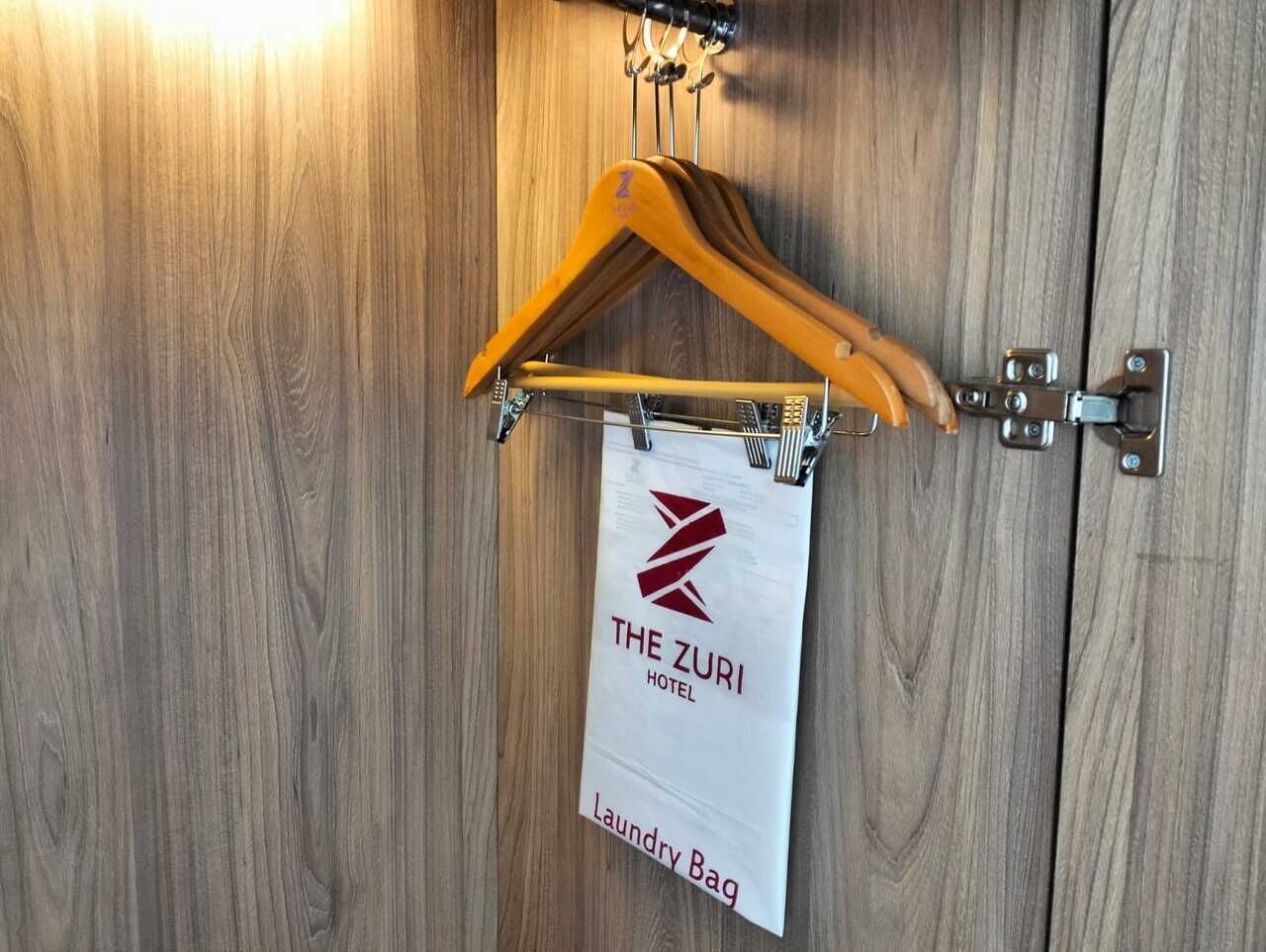 A wooden door with a hanger and a sign indicating a laundry bag area at The Zuri Hotel.