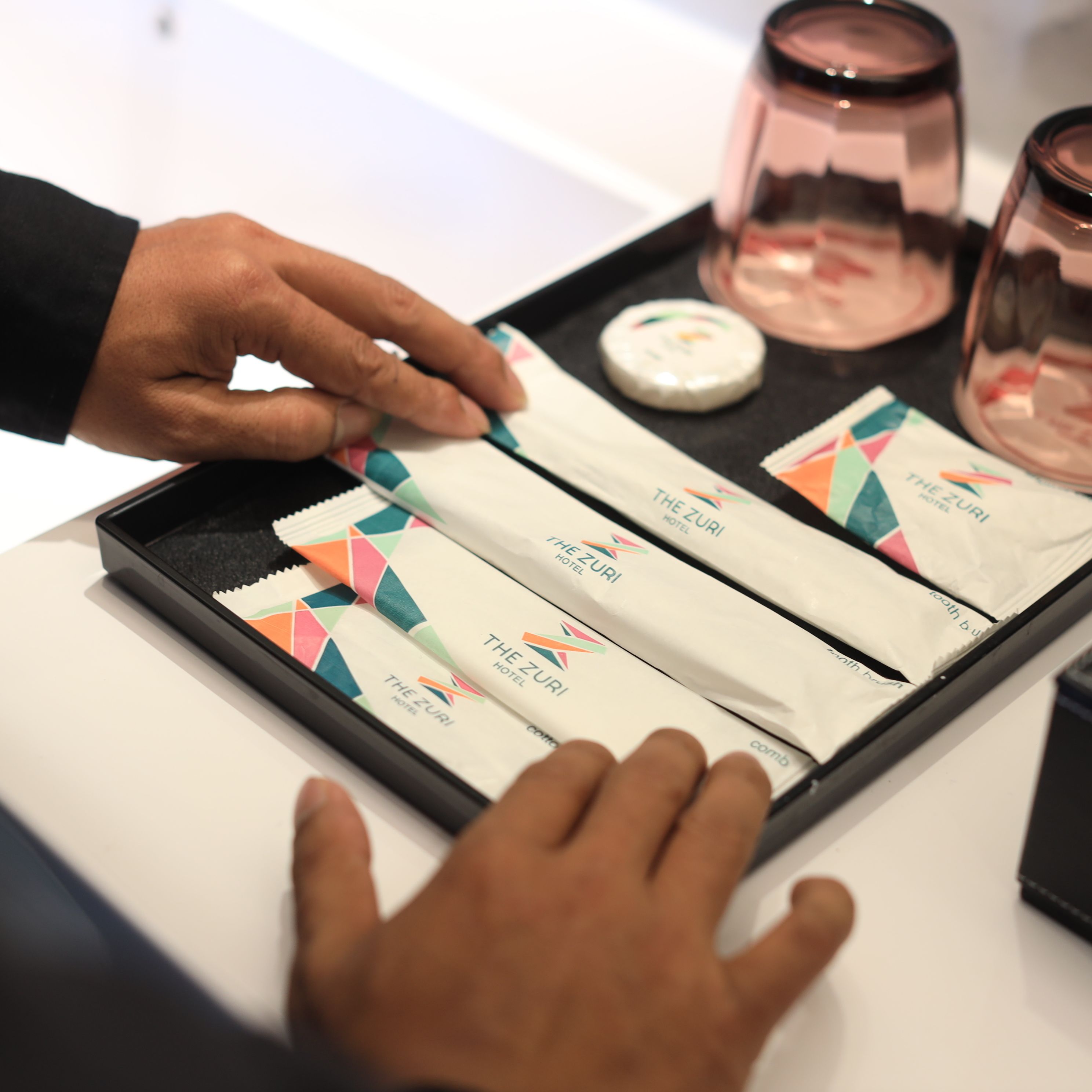 A tray with four hotel name tags and a small container.