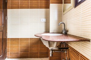 A bathroom with a sink, mirror, and a window with blinds.