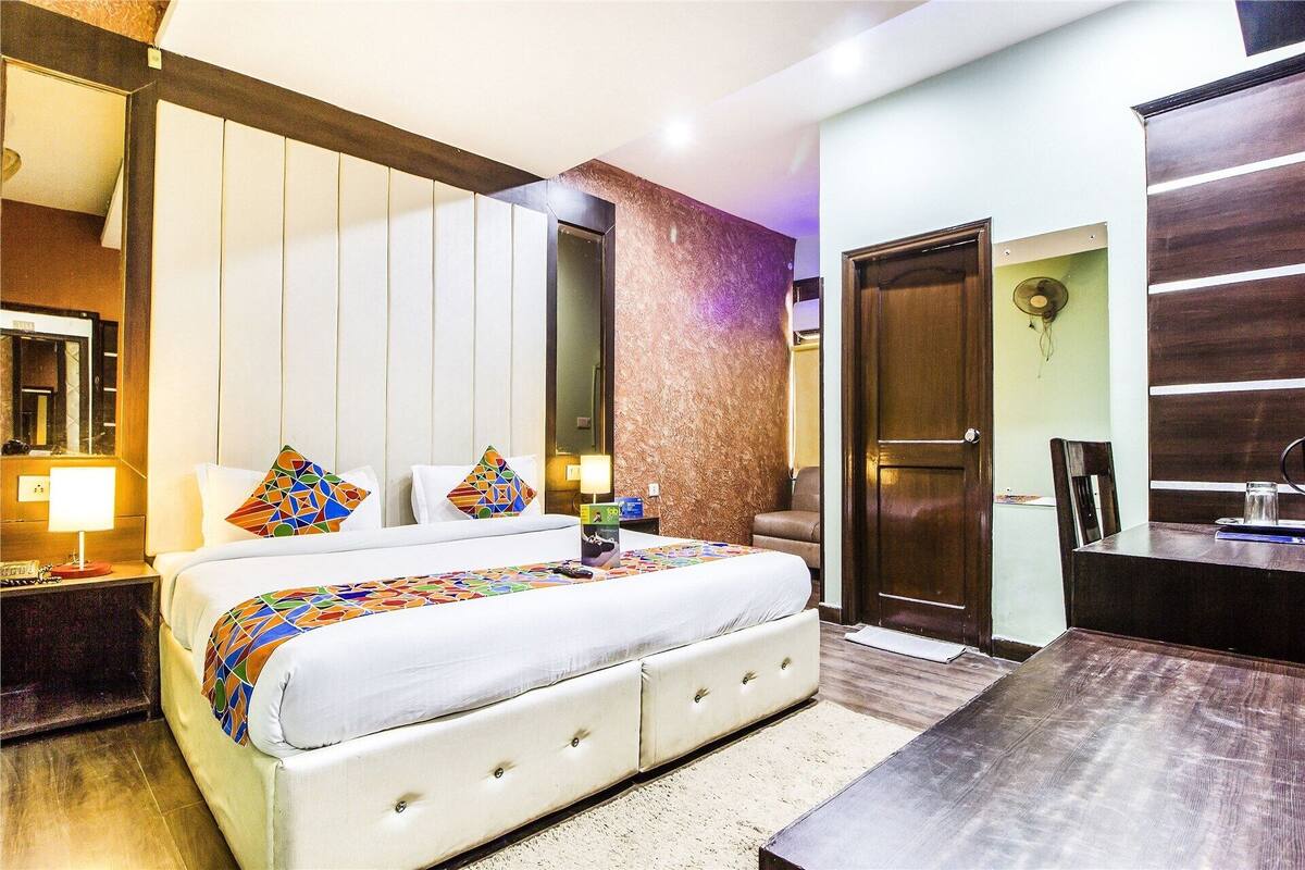 A hotel room with a bed, bedside table, lamp, and a mirror.