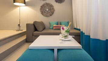 Una sala de estar moderna con una mesa blanca, cojines color turquesa, un sofá y decoración mural.