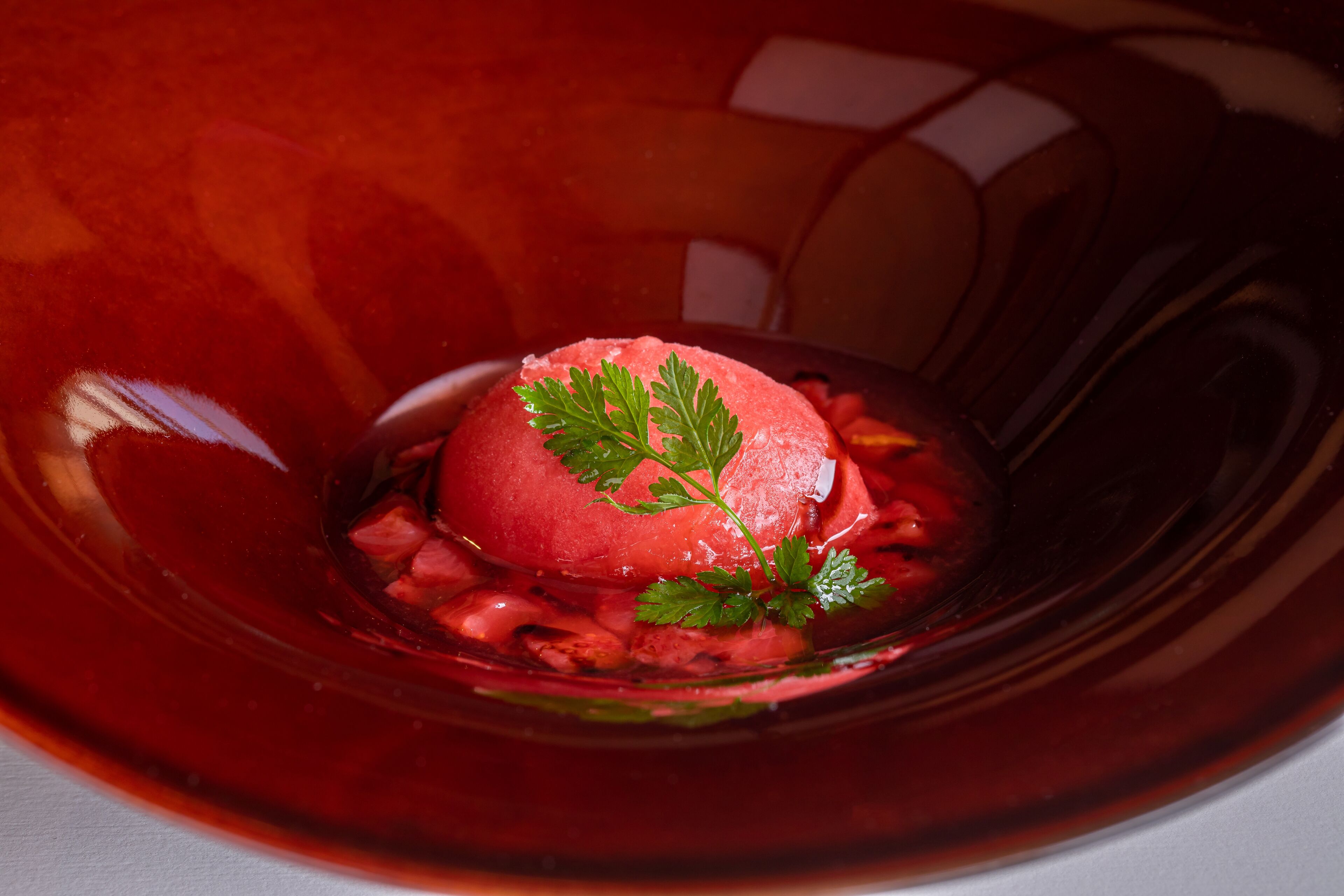 Un dessert servi dans un bol en verre, agrémenté d’une garniture.