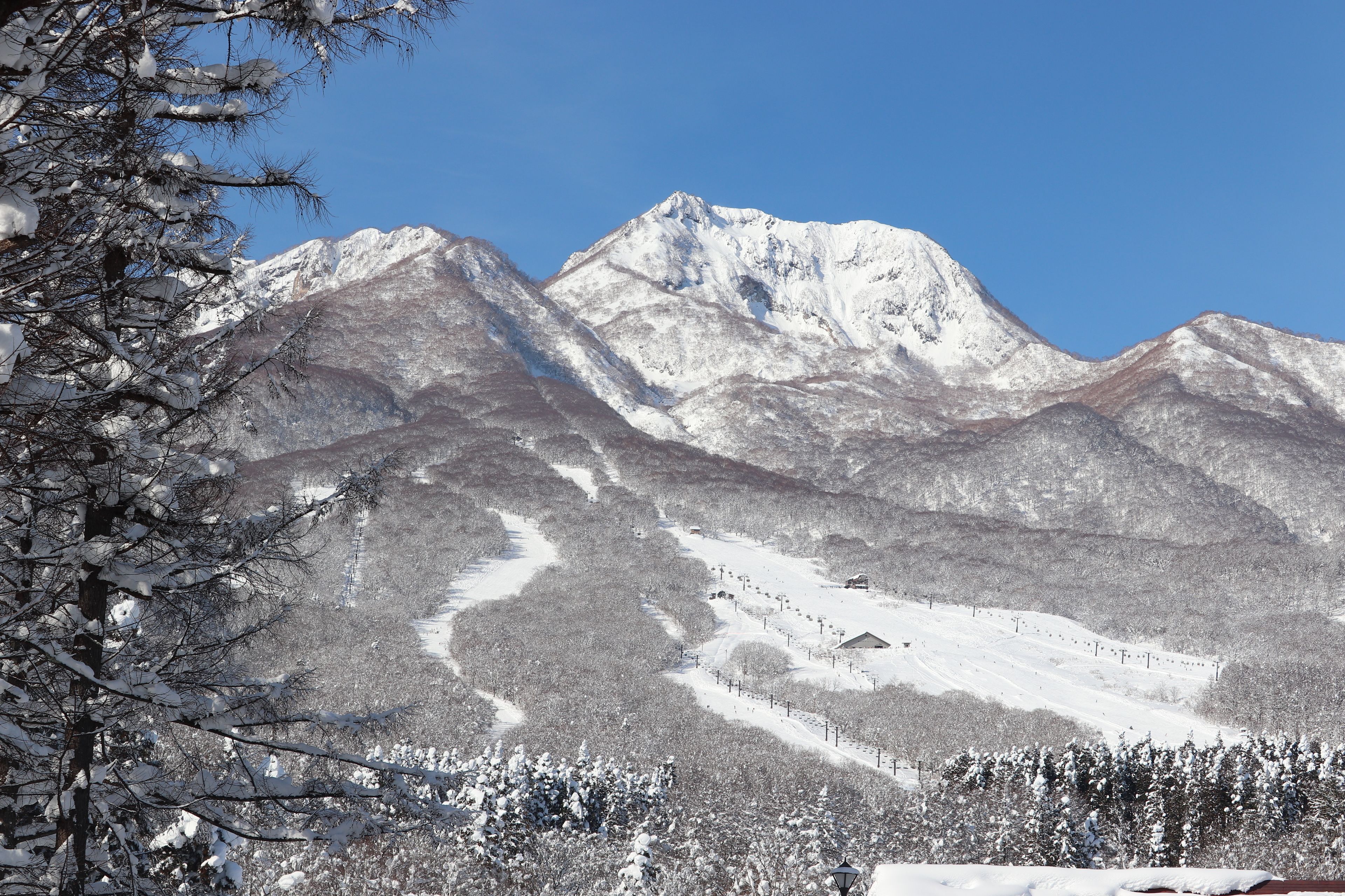 A mountain landscape with snow-covered peaks and a ski slope.