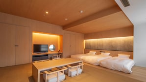 A modern hotel room with a wooden ceiling, a flat-screen TV, a bed with white bedding, and a wooden table with benches. - Lime Resort Myoko (Myoko)